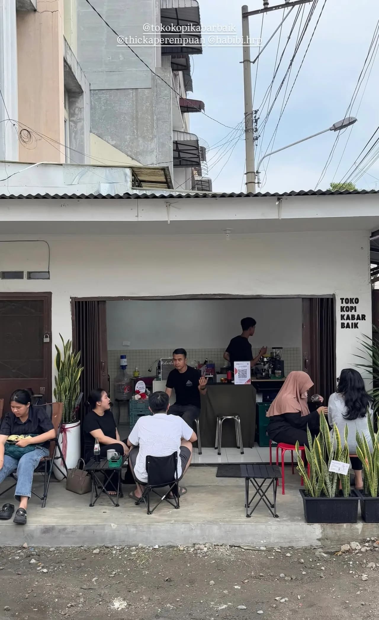 Tampak depan toko dengan tamu di kursi outdoor, signage TOKO KOPI KABAR BAIK terlihat jelas di dinding