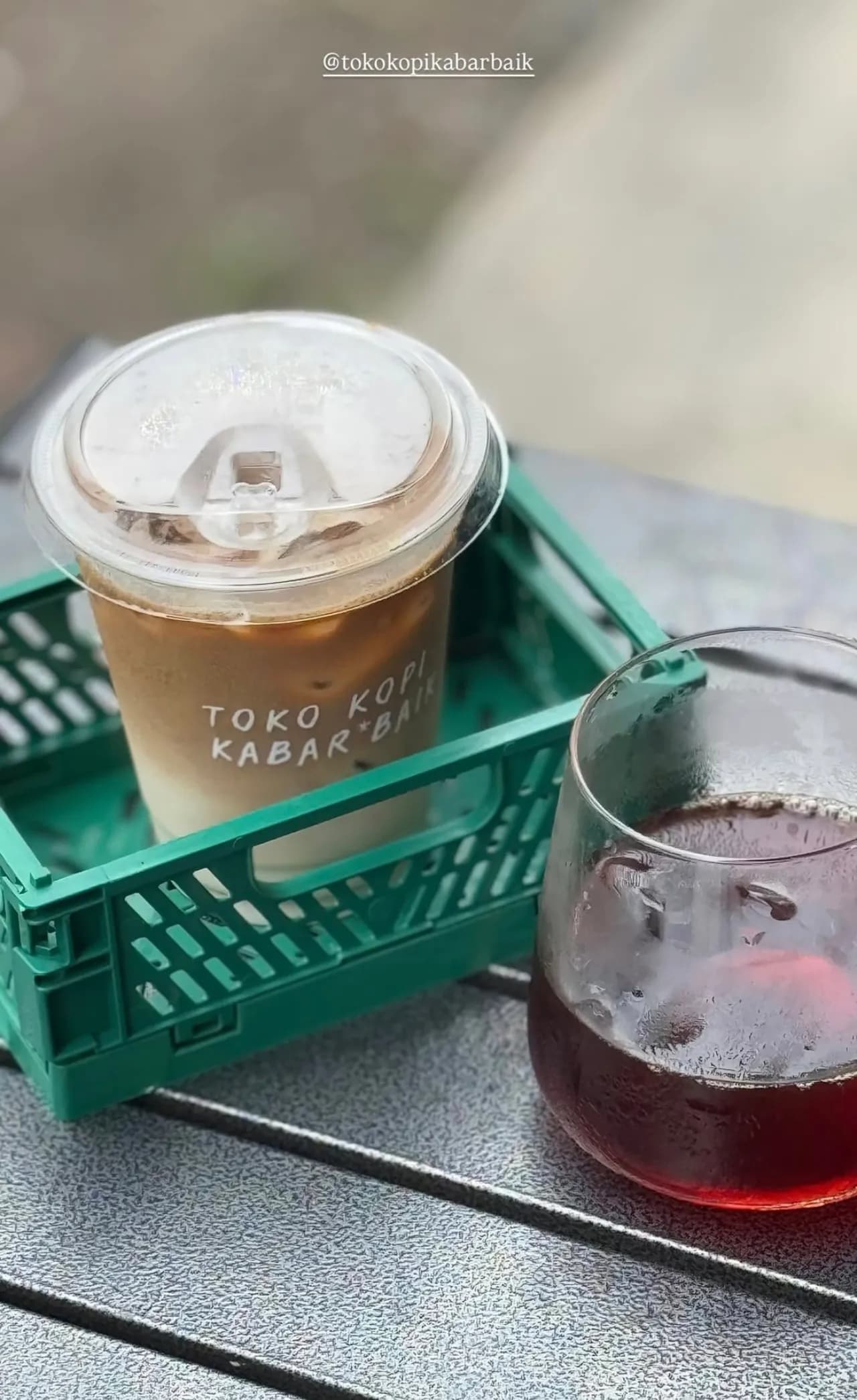 Dua menu signature Toko Kopi Kabar Baik: Kopi Susu Kabar Baik dan Orange Americano disajikan di crate hijau